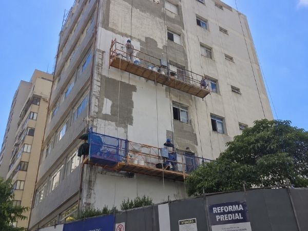 Reforma predial em prédio alto com trabalhadores suspensos em balancim aplicando revestimento na fachada, placa de obra 'Reforma Predial', fotografia realista de reforma de edifício